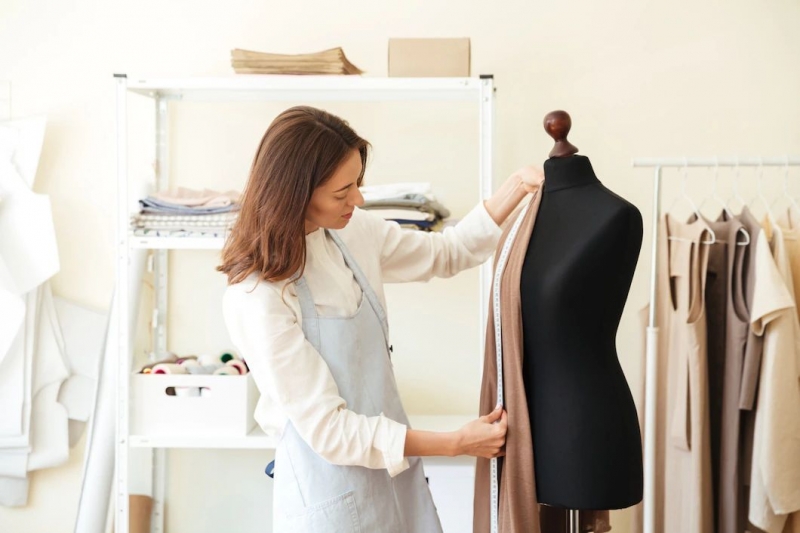 brunette-seamstress-apron-measuring-beautiful-fabric-black-dummy-workshop-171337-7341
